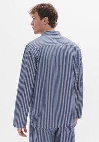 Csíkos pamut pizsama szett tengerészkék és fehér színben, hosszú ujjakkal, gallérral és mellzsebbel; laza szabású és könnyű textúrájú.