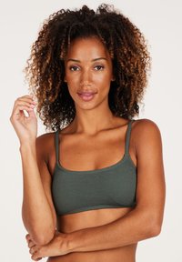 Bralette verde scuro con texture, a forma rettangolare e finitura liscia. Regolabile per una vestibilità comoda.