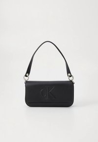 Mala preta de pele com forma retangular plana, logótipo "cK" gravado a relevo, alça ajustável e detalhes em metal prateado.