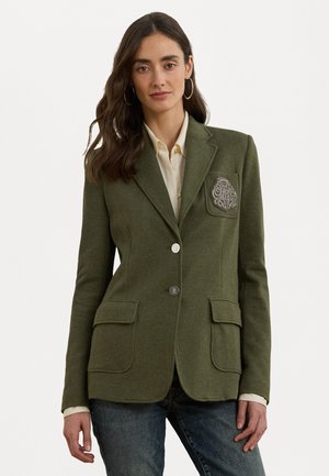 Olivgrön herringbone-blazer med utskurna slag, två framsidans fickor, silverfärgad knappstängning och en dekorativ patch på vänster bröst.