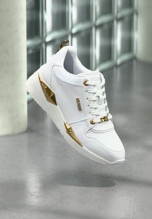 White sneakers made of leather, featuring gold accents, textured sides, and lace closure; sleek design with a reinforced heel and logo detail.
