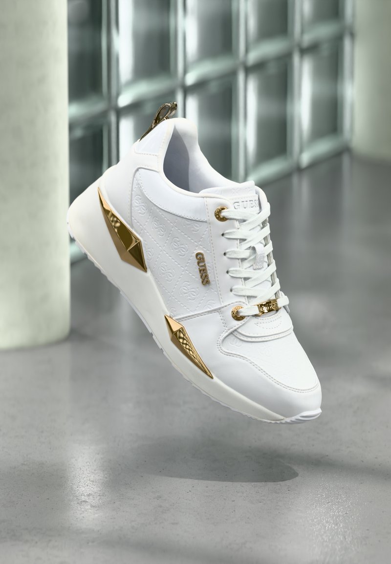 Białe sneakersy wykonane ze skóry, z złotymi akcentami, teksturowanymi bokami i sznurowanym zapięciem; elegancki design z wzmocnionym piętą i detalem z logo.