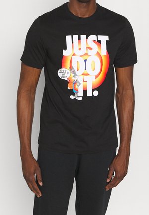 Personne portant un t-shirt noir avec un grand texte "JUST DO IT." et Bugs Bunny tenant un ballon de basket disant "Ehhh, quoi de neuf Doc ?" sur le devant.