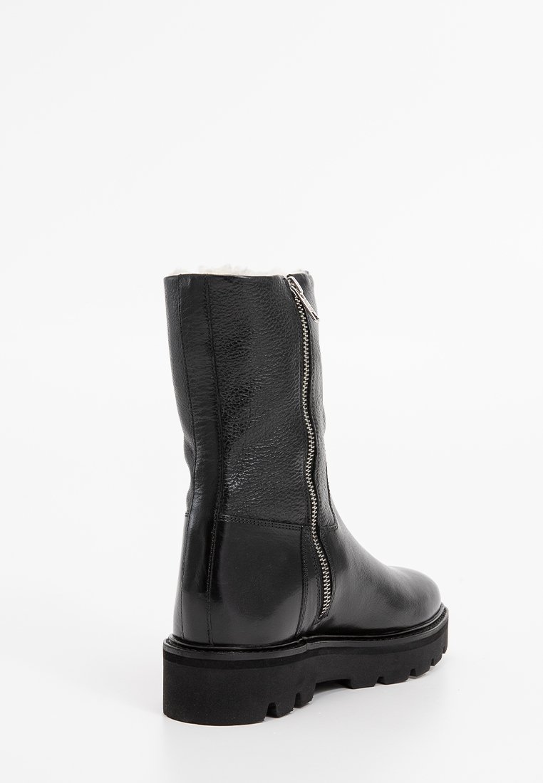 Zwarte leren enkellaarzen met een gestructureerde afwerking, een rits aan de zijkant en een chunky zwarte plateauzool. Het interieur heeft een zachte voering.