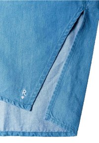 Svijetloplavi traper s detaljem bočnog proreza i malim bijelim izvezenim slovom "R" s srcem u blizini ruba.