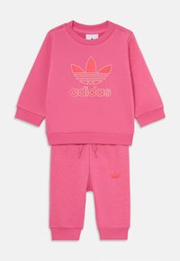 Ensemble en coton Adidas rose comprenant un sweatshirt à col rond avec logo imprimé et un pantalon assorti avec poches et taille élastique.