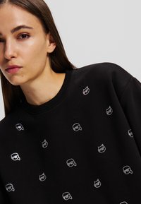Schwarzer Sweatshirt aus Baumwollmischung mit metallischen silbernen Akzenten in einem verspielten Muster über den Stoff. Rundhalsausschnitt, lockere Passform.