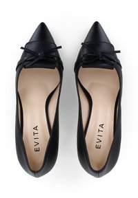 Scarpe con tacco alto in pelle nera, con punta a punta e un piccolo fiocco decorativo. Presentano un design elegante e una soletta beige con il nome del marchio "EVITA."