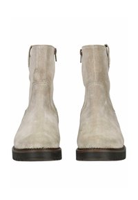 Botines de ante beige con textura suave, punta redondeada y cremallera trasera. Suela de goma negra con detalle de costura a lo largo del borde.