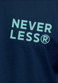 Marineblaues Gewebe mit fettgedrucktem, hellblauem Text, der "NEVER LESS®" lautet. Der Text hat eine moderne serifenlose Schriftart mit einem eingetragenen Markenzeichen.