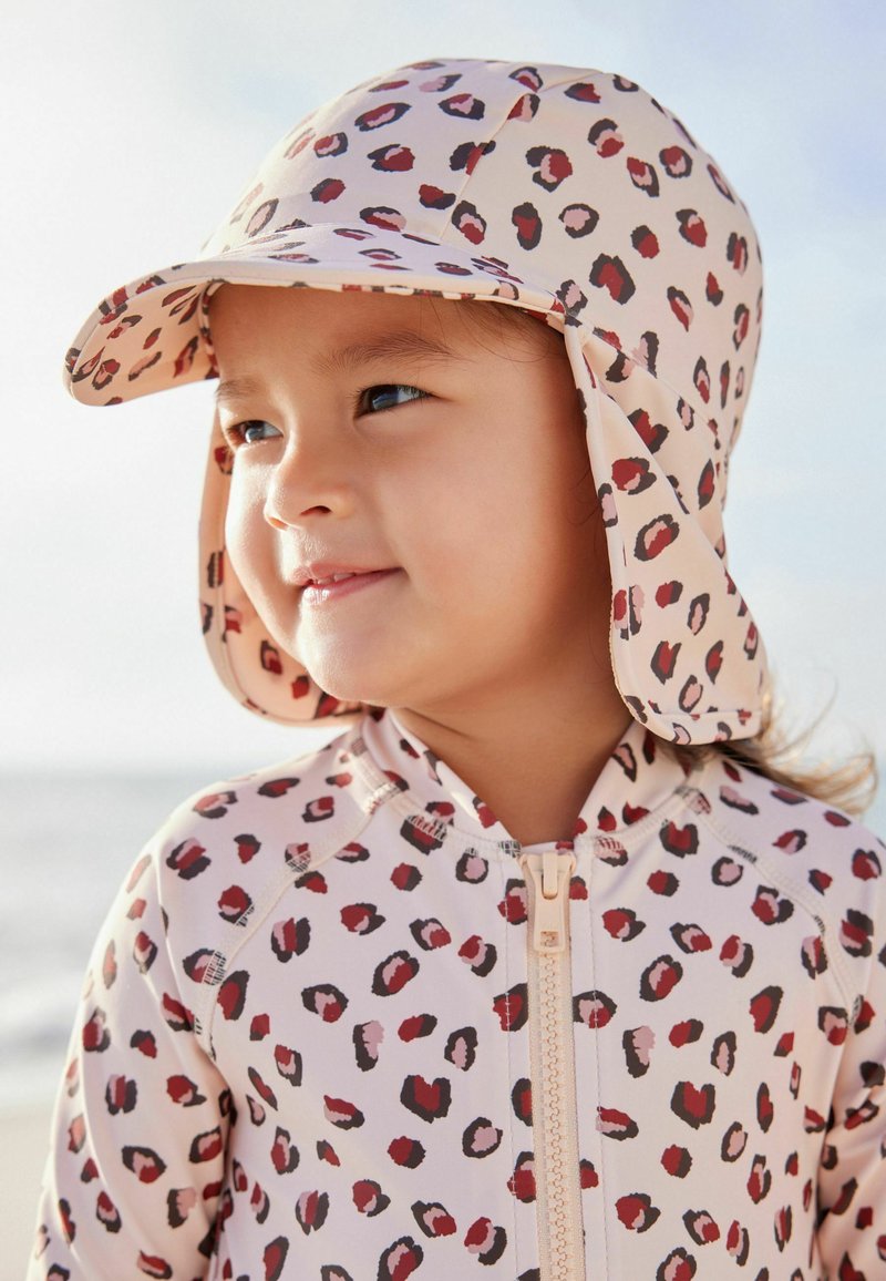 Cuffia da nuoto e rash guard con stampa leopardata in tonalità di rosa e rosso, caratterizzati da una cerniera frontale e una protezione sul cappuccio.