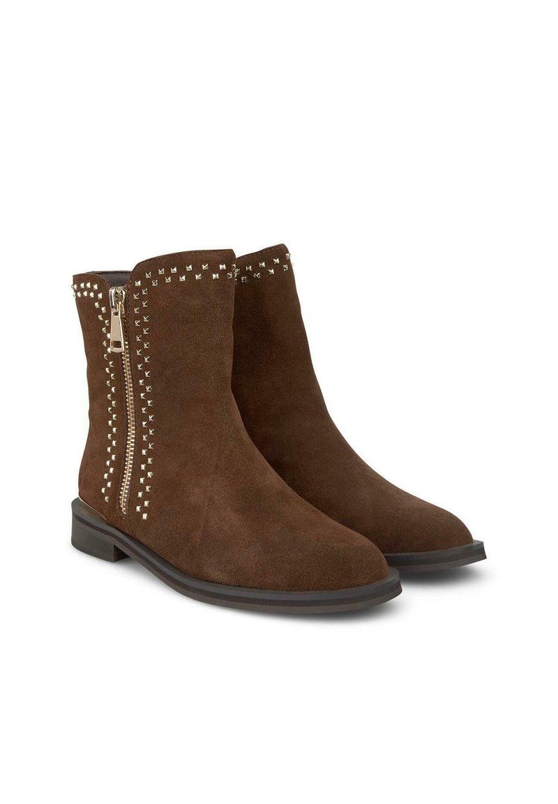 Botas de tobillo de ante marrón con cremallera lateral que presentan tachuelas metálicas a lo largo de la cremallera y el borde superior. Suela plana con un ligero tacón.