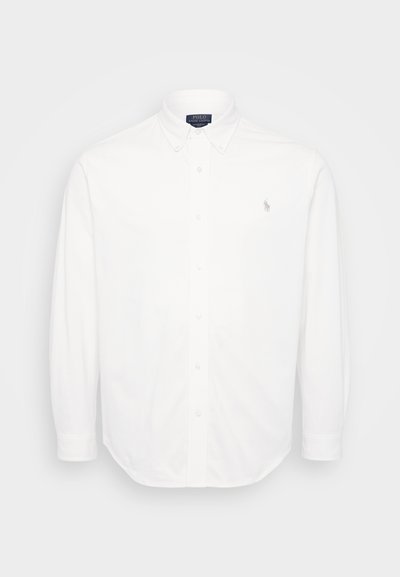 Chemise blanche à manches longues avec un col boutonné, des boutons sur le devant et un petit logo brodé sur la poitrine gauche. Fabriquée en coton.
