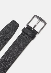 Cintura in pelle nera con finitura texture, dotata di una fibbia e anello in metallo argentato, progettata con un'estremità a taglio dritto.