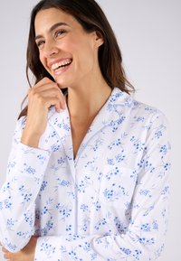 Chemise de pyjama à motif floral en tissu blanc avec des accents bleus et gris, dotée d'une poche poitrine, d'un col classique et d'une fermeture à boutons.