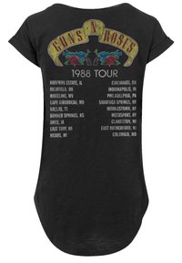 Black short-sleeved t-shirt featuring a vintage Guns N' Roses logo and tour dates, adorned with red roses and yellow accents. Soft fabric.