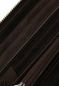 Interno di un portafoglio marrone con molteplici scomparti per carte, un vano con zip e una fodera in tessuto texturizzato. Presenta cuciture robuste e una zip liscia.