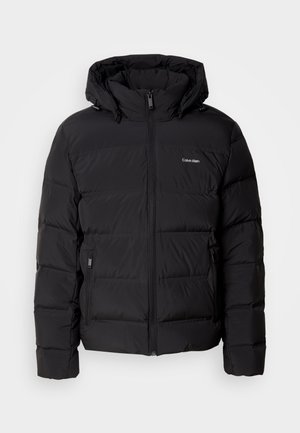 Zwarte pufferjas met een ritssluiting aan de voorkant en een verstelbare capuchon. Bevat gequiltte panelen, twee zijzakken en een klein logo op de borst.