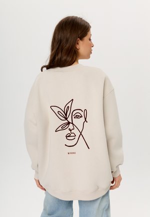 Beiger Sweatshirt mit Rundhalsausschnitt, das auf der Rückseite ein minimalistisches braunes Linienkunstdesign eines Gesichts und eines Blattes zeigt. Lockere Passform.