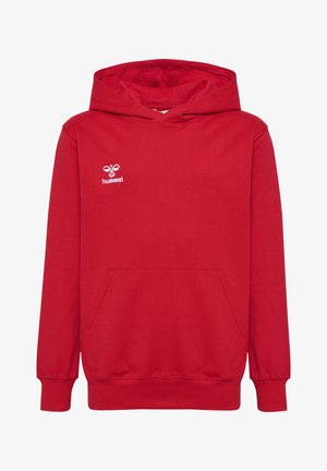 To børn iført matchende røde hættetrøjer, mørkeblå bukser og hvide sneakers mod en ensfarvet grå baggrund.