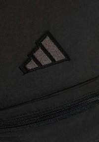 Schwarzer Stoff-Rucksack mit einem auffälligen, gestickten Adidas-Logo mit drei parallelen Streifen und einem Reißverschluss-Detail am unteren Rand.