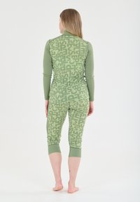 Green athleisure set made of stretchy fabric with a bold, repeated text pattern. Features long sleeves and cropped leggings, with fitted design.