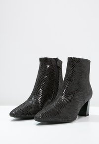 Bottes noires à chevilles avec un bout pointu, un motif en cuir de serpent texturé et une fermeture éclair sur le côté, comportant un petit talon épais.