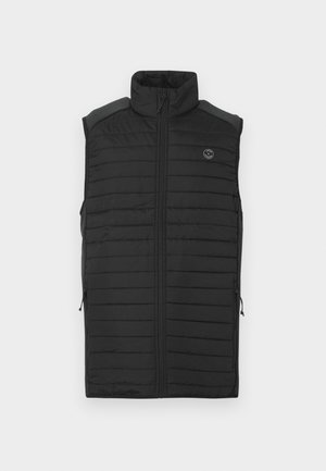 Chaleco negro sin mangas con cuello alto, diseño acolchado, cremallera frontal y dos bolsillos laterales. Presenta un logo en el pecho.