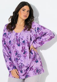 Lila Bluse mit langen Ärmeln, mit Falten am Ausschnitt, ausgestattet mit detaillierten rosa und blauen Blumenmustern auf einem weichen Stoff.