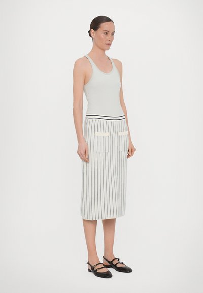Halli halli tank top, mida on kombineeritud keskpikkade triibuliste seelikutega, millel on ees taskud ja kontrastne vöökoht. Mustad rihmadega kingad täydentavad välimust.