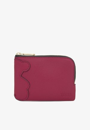 Piccolo portafoglio in pelle rosa testurizzata con cerniera dorata e nome del marchio "TOUS" in rilievo nell'angolo in basso a destra.