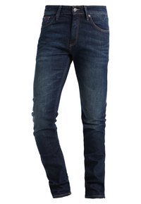 Tmavě modré džíny z denimu s úzkým střihem, pěti kapsami a kontrastním oranžovým prošíváním. Mají zip a kovové zapínání.