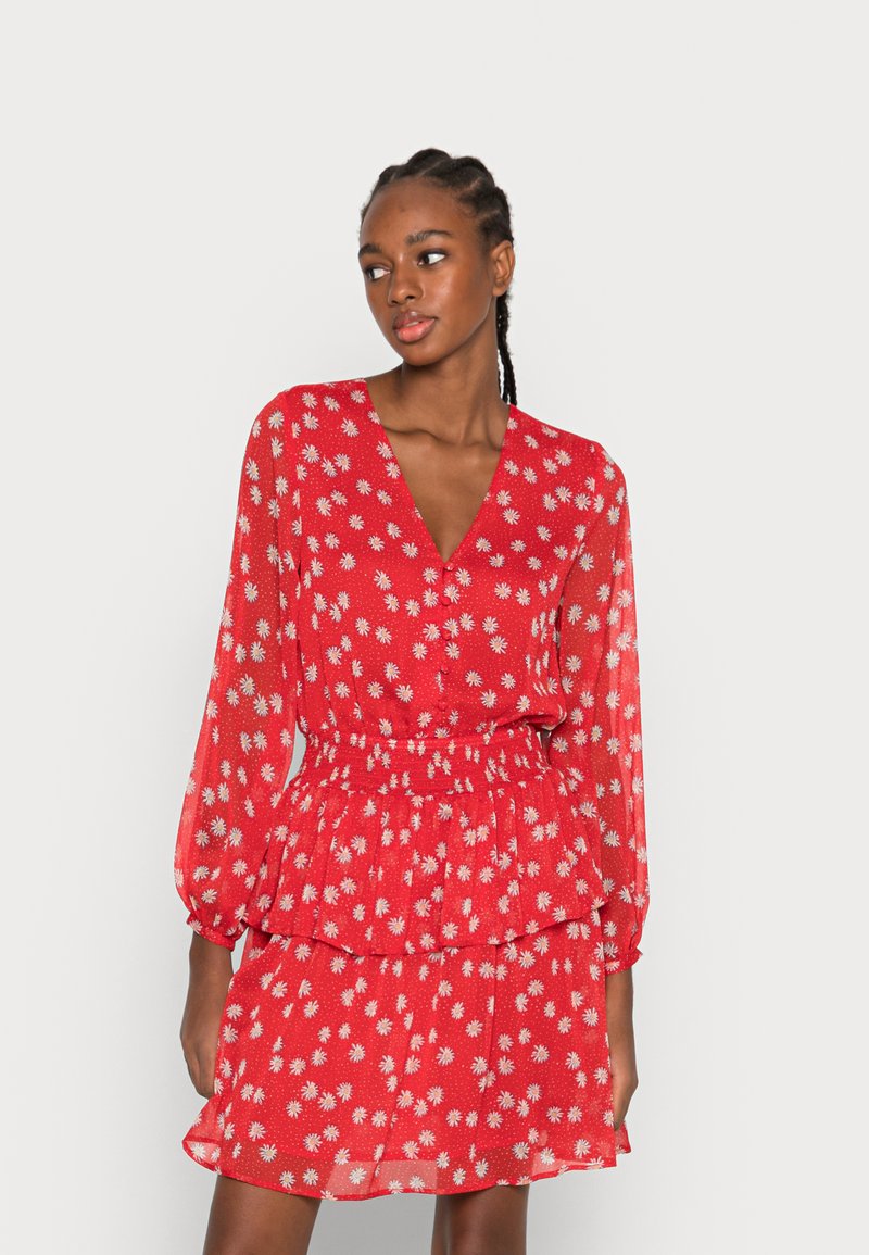 Vestido floral vermelho com decote V profundo, mangas longas, cintura franzida e peplum em camadas. Feito de tecido leve com padrões de flores brancas.