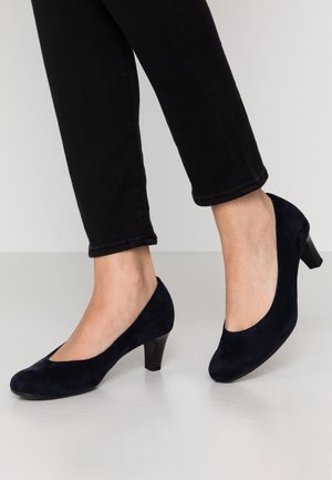 Granatowe zamszowe szpilki z okrągłym noskiem i małym słupkiem, charakteryzują się gładką fakturą i klasyczną sylwetką.