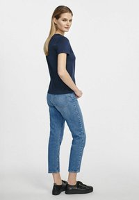 Granatowa koszulka z krótkim rękawem o dopasowanym kroju, zestawiona z jasnoniebieskimi dżinsami do kostek i czarnymi sznurowanymi butami.