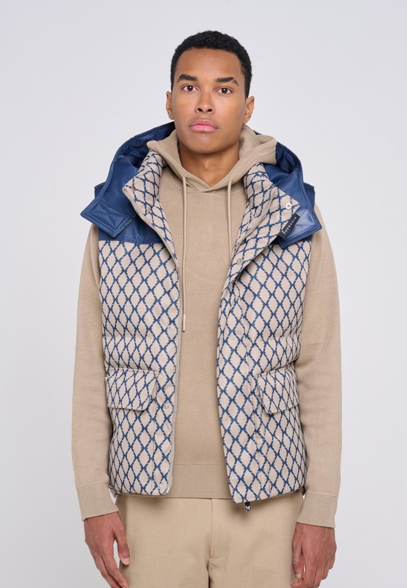Gilet trapuntato beige con cappuccio blu, caratterizzato da un motivo a rombi, due tasche frontali e chiusura con zip. Tessuto morbido con un aspetto texturizzato.