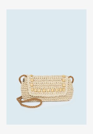 Bolso de hombro rectangular beige tejido a ganchillo con adornos de cuentas de madera en la solapa y correa marrón trenzada sobre fondo azul pálido.