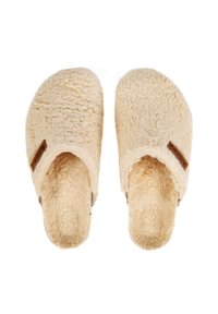 Chaussons en crème, moelleux, avec une texture douce, un design ouvert à l'arrière et une étiquette brune sur le côté. Bout rond et doublure en peluche.