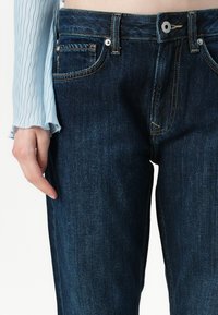 Dark blue denim jeans with a straight leg design. Features gold stitching, five pockets, and a button closure at the waistband.