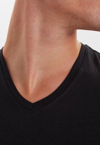 Black cotton t-shirt with a V-neck design, smooth texture, and minimalist style, showing neck area with natural skin tone.