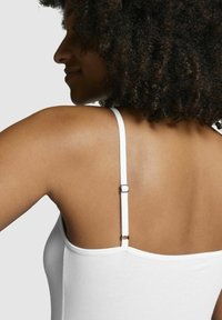 White camisole with thin straps, featuring a metal adjustment slider. Smooth fabric with a fitted silhouette, showing skin tone on the back.