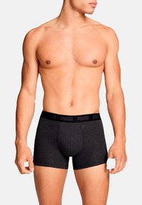 Schwarze Boxershorts aus Baumwolle mit einem elastischen Bund, der mit einer Marke bedruckt ist. Die Shorts sind eng anliegend, haben eine mittlere Oberschenkellänge und eine glatte Textur.