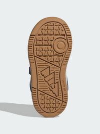 Gumowa podeszwa buta z teksturowanym wzorem bieżnika. Zawiera okrągły akcent i kanciaste wzory, głównie w odcieniach brązu i beżu.