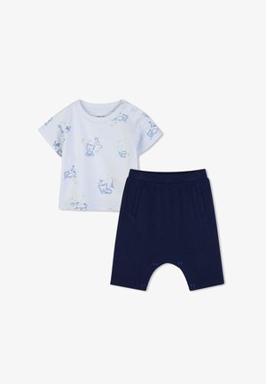 Chemise blanche à manches courtes pour bébé avec imprimés d'animaux bleus, associée à un short bleu marine doté de poches avant et de boutons pression à l'entrejambe.