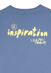 Blauwe katoenen t-shirt met gedurfde, gele grafische tekst "WEES inspiratie" en "x SCALPERS COMPANY" in gestileerde lettertypen. Klassiek ronde hals ontwerp.