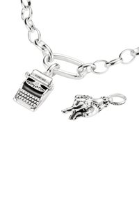 Silberfarbene Kettenhalskette mit einer Schreibmaschine und einem Handanhänger. Die Teile sind mit schwarzen Akzenten und gravierten Elementen verziert.