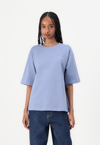 Svetlomodré bavlnené tričko s krátkymi rukávmi, klasickým výstrihom a malým bielym logom Calvin Klein na ľavej hrudi. Voľný strih, hladká textúra.