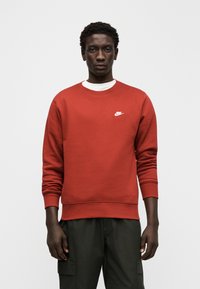 Sweatshirt vermelho de algodão com gola redonda clássica, punhos e bainha canelados. Apresenta um pequeno logótipo branco da Nike no peito.