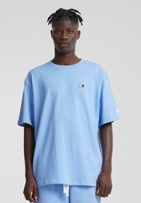 Light blue oversized cotton t-shirt featuring a small black logo on the chest and short sleeves, paired with matching light blue shorts.
