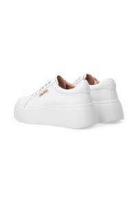 White sneakers with a smooth leather upper, rounded toe, and contrasting tan accents on the heel. Chunky white platform sole.